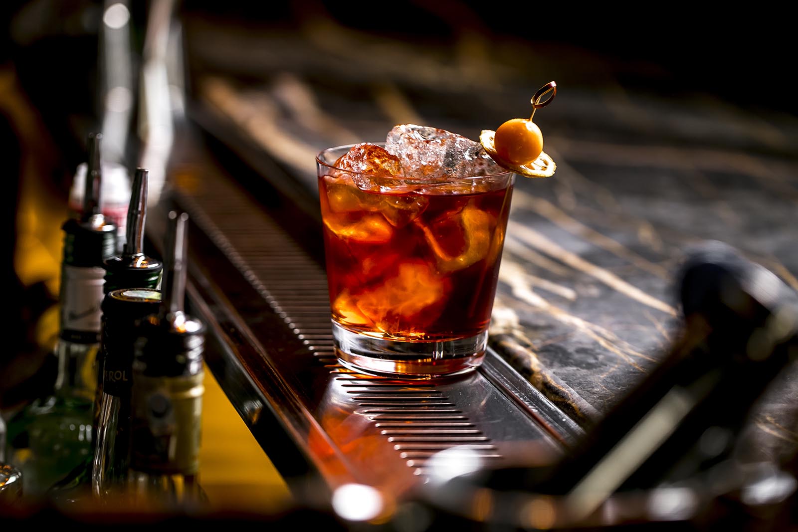 a cocktail glass with ice cubes garnished with dried lemon and fruit